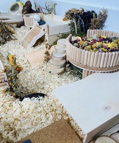 an assortment of fake flowers and plants in a miniature garden setting with wooden toys on the floor