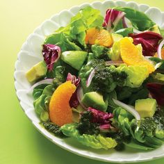 a salad with oranges, broccoli and avocado on a white plate