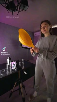 a woman holding an orange frisbee in her hand while standing next to a table