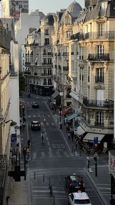 a city street filled with lots of traffic and tall buildings on either side of it