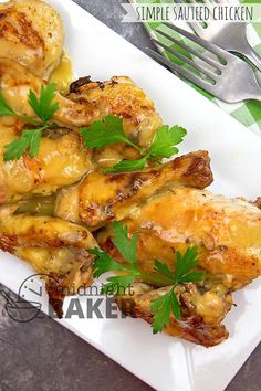 some chicken is on a white plate with green garnish and parsley sprigs