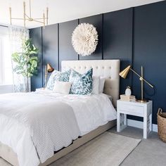 a bed with white sheets and pillows in a room that has dark blue painted walls