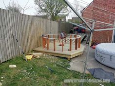 a backyard with a fence and some tools on the ground next to a hot tub