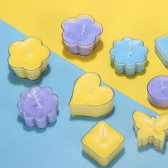 several candles are arranged on a blue and yellow background with hearts, flowers, and soap cubes