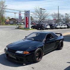 a black sports car parked in front of a gas station with other cars behind it