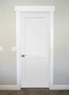 an empty room with a white door and carpet