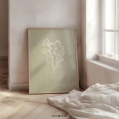 a framed photograph sitting on top of a wooden floor next to a white bed in a room