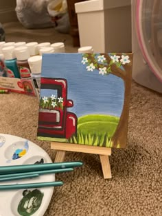 an easel sitting on the floor next to some paintbrushes and other art supplies