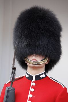 a man in a red uniform holding a knife and wearing a black hat with fur on it