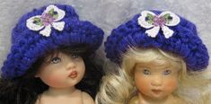 two dolls are wearing hats with flowers on the top one is blonde and the other is blue