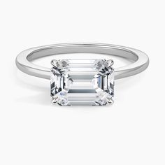 an emerald cut diamond ring on a white background