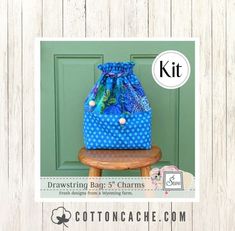 a blue bag sitting on top of a wooden table next to a green door with the words, drawing bags 3 charms