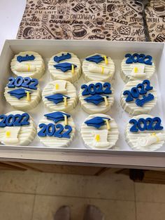 cupcakes decorated with royal blue and white frosting are displayed in a box