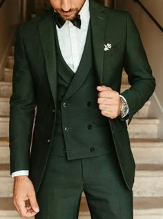 a man in a green suit and bow tie is standing on the stairs with his hands in his pockets