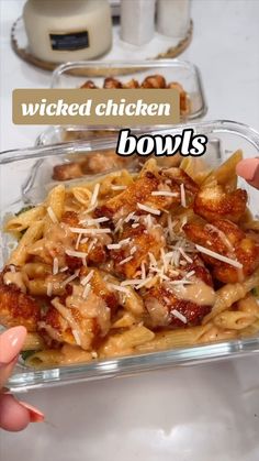 someone is holding up a glass dish with chicken and pasta in it