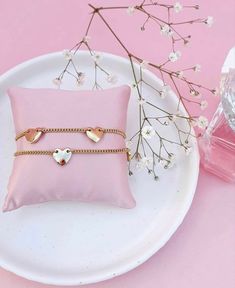 two bracelets sitting on top of a white plate next to a pink flower vase