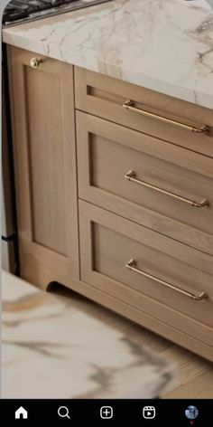 an appliance with marble counter tops and gold pulls on the cabinet door handles