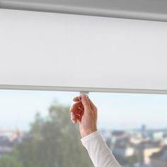 a person is adjusting the blinds in front of a window