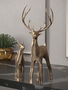 two brass deer statues sitting on top of a table