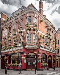 an old building with flowers growing on it's side in the middle of town