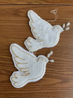 two white doves with gold accents on a wooden surface