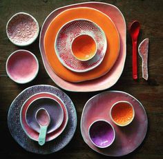 an assortment of colorful dishes and utensils laid out on a wooden table top