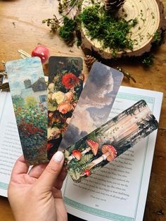 a person holding four cards in their hand on top of an open book with flowers