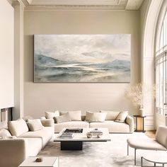 a living room filled with furniture and a large painting on the wall above it's windows