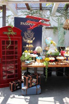 a table that has some suitcases and cakes on it in front of a red phone booth