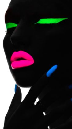 a woman's face with neon green and pink nail polishes on her hands