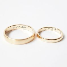 two gold wedding rings with names engraved on the inside and outside, sitting side by side