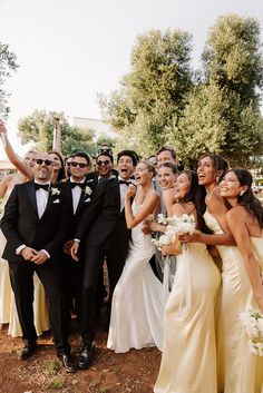 a group of people standing next to each other in front of some trees and bushes