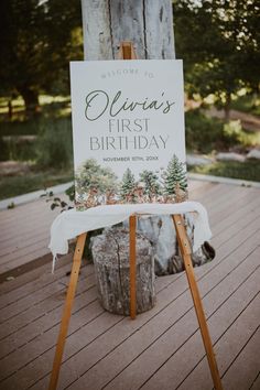 a welcome sign sitting on top of a wooden easel next to a white table cloth