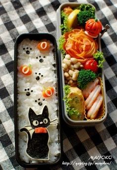 two bento boxes filled with food on top of a table