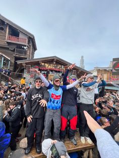 a group of people standing on top of a wooden platform with their arms in the air