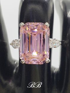 a pink diamond ring with three diamonds around it