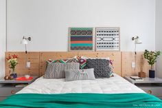 a bed with pillows and blankets in a bedroom next to a wall mounted art piece