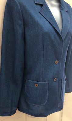 "Okay, this polyester blazer is awesome! It is faux denim in a stretchy polyester knit fabric. It is sized vintage 11/12, but by today's standards should fit a 6-8. See measurements below. This could be worn so many ways! The red stitching gives it western flare, but it also has a mod 70s vibe. I love it! It's in mint condition & hard to believe it's over 40 years old. Please note the vintage buttons ~ Remington Express 20GA. I've seen the buttons alone going for several dollars a piece. Sna Classic Tailored Denim Jacket With Pockets, Classic Denim Blue Blazer With Pockets, Tailored Denim Jacket With Notch Lapel And Pockets, Tailored Denim Blazer With Button Closure, Tailored Denim Blazer With Pockets, Formal Tailored Denim Outerwear, Tailored Denim Outerwear For Formal Occasions, Fitted Denim Jacket With Notch Lapel In Denim Blue, Fitted Denim Blue Denim Jacket With Notch Lapel