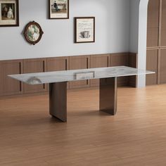 a glass table sitting on top of a hard wood floor next to a wall filled with pictures