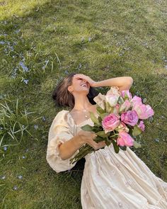 a woman laying on the ground holding a bouquet of flowers in her hand and laughing