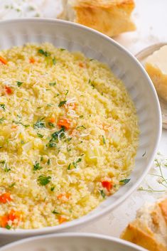 a white bowl filled with rice and carrots next to slices of bread on a table