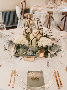 the table is set with gold and white flowers, silverware, and candlesticks