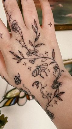 a woman's hand with flowers and butterflies tattooed on the middle of her palm