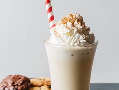 there is a drink with whipped cream and cookies on the table next to it,