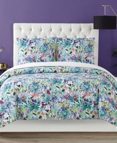 a bed with purple walls and white headboard in front of a blue flowered wall