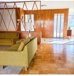 an empty living room with wood paneling and green couches in the center area