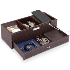 an open brown leather jewelry box with keys, watch and other items in it on a white background