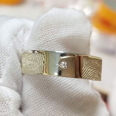 a gold ring with a diamond on it sitting on top of a white towel in front of a mirror