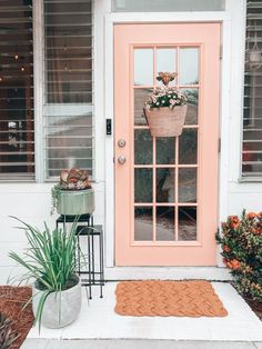 a pink front door with potted plants on the side