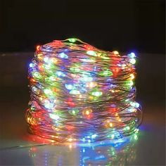 multicolored lights on a white surface in the dark, with one wire wrapped around it